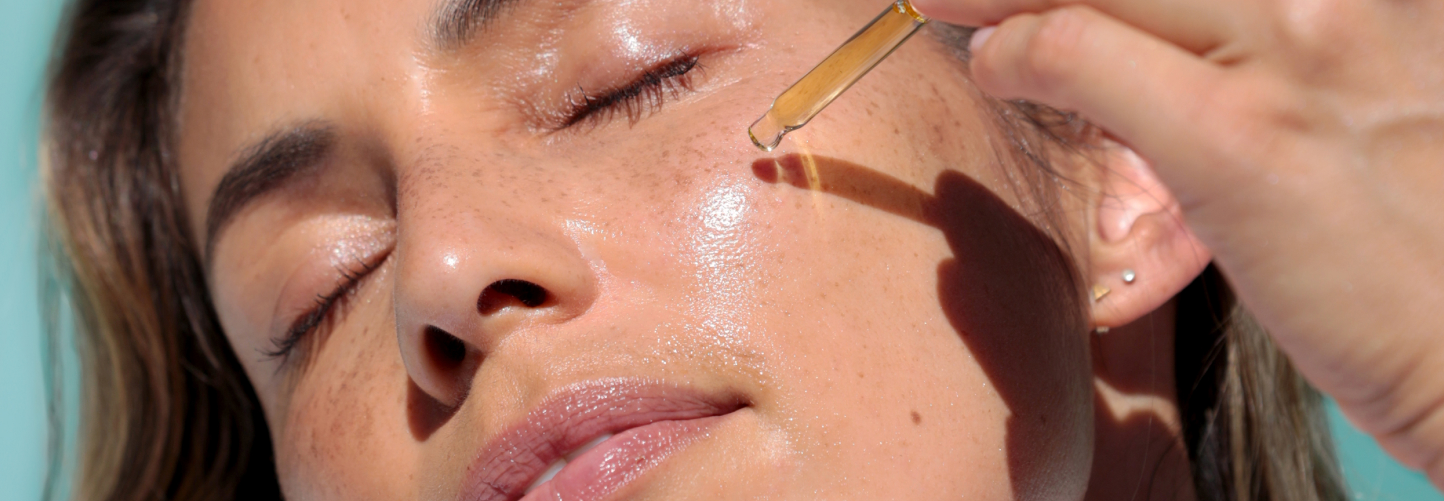 model applying a dropper-full of serum to their cheek