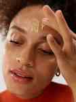 close up of a girl applying skin care on her forehead and looking down