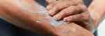 closeup of a man rubbing lotion into his arm