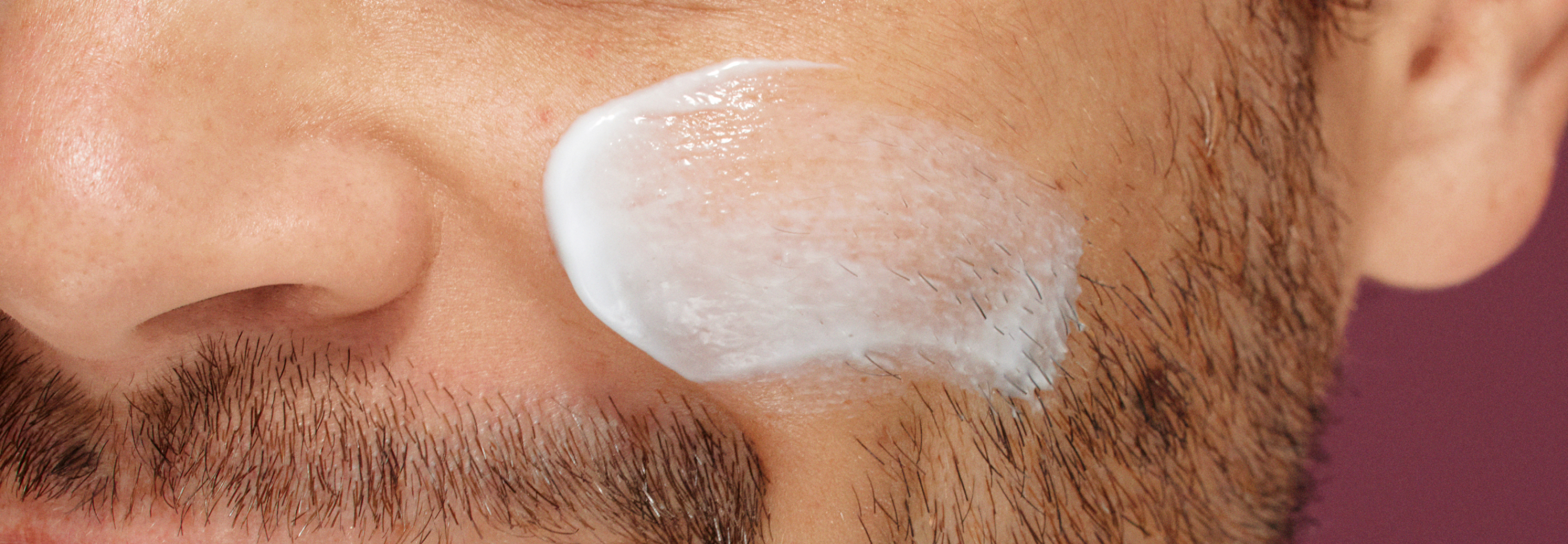 model applying moisturiser to his cheek