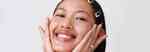 smiling model holding their face