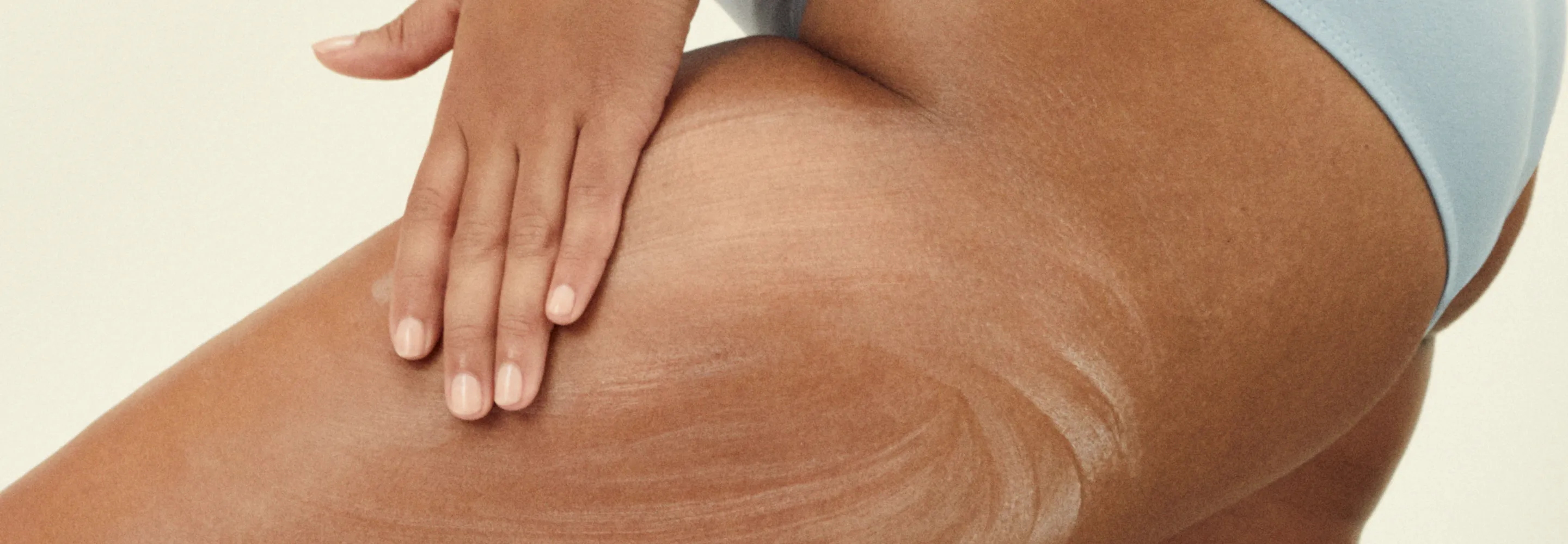 model applying body lotion to their leg