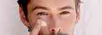 model applying eye cream to his undereye