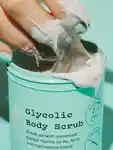 Someone dipping their hand into a tub of Glycolic Body Scrub