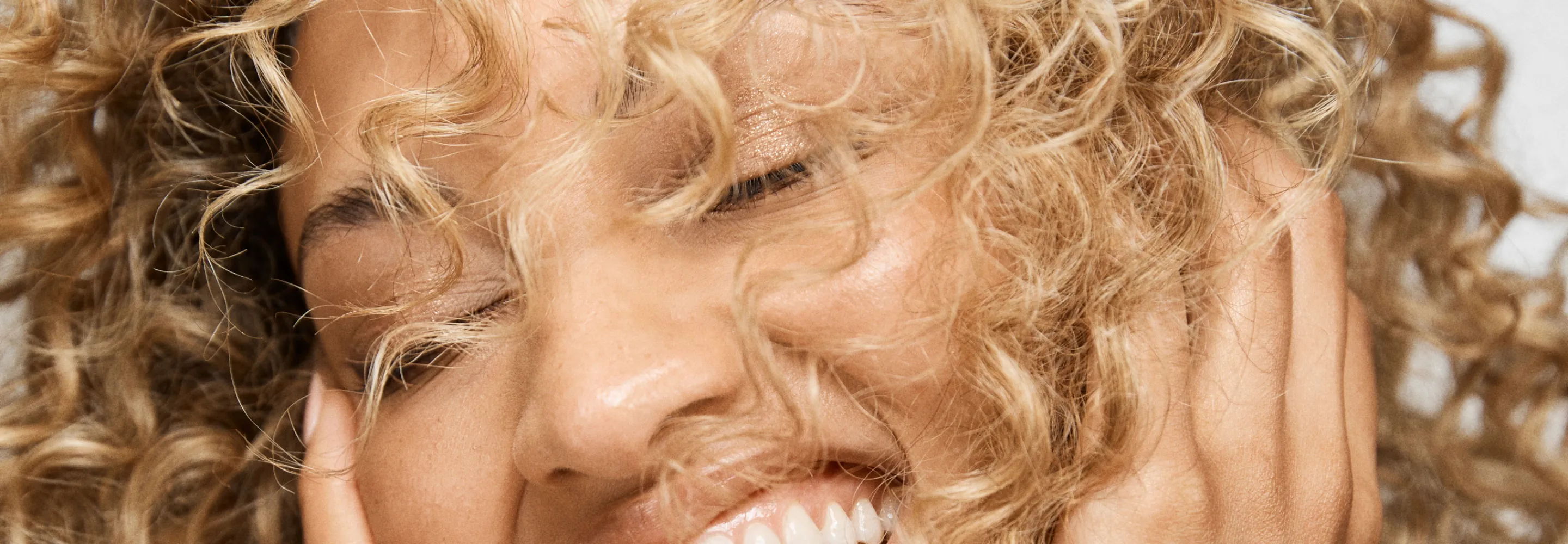 model with curly hair laughing