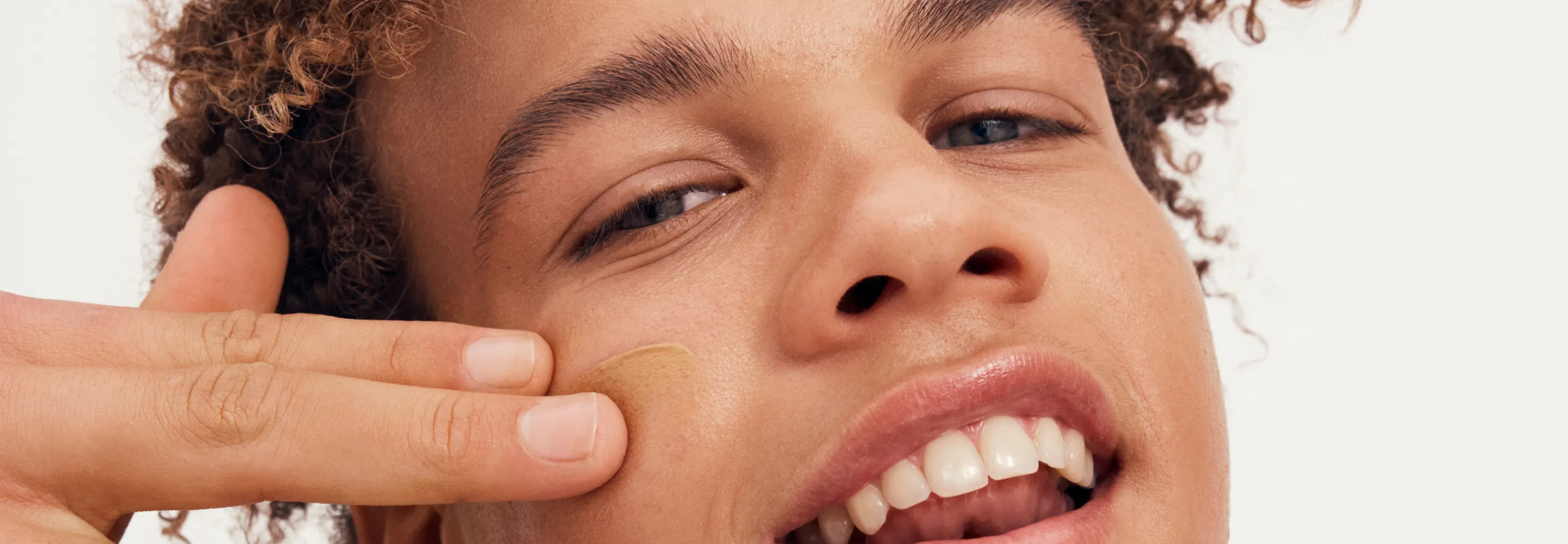 model applying concealer to their cheek with two fingers