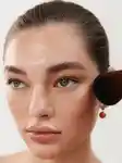 close up of a girl looking to the side holding a makeup brush to her cheek