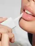 Closeup of a model applying kosas wet lip oil to their lips