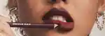 closeup of a model holding a dark purple lip liner on their lips