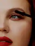 closeup of a model applying mascara to their eyelashes