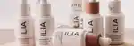 bottles of the ilia super serum skin tint scattered on a table