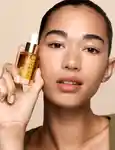 Model holding mecca cosmetica to save face sunscreens: SPF50+ superscreen, SPF50+ brightening sun serum and SPF30 facial sunscreen