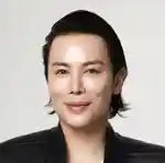 A person smiling at the camera in a black leather jacket