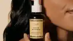 Model with curly hair holding Ceremonia product