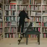Costa Brazil in front of his expansive book shelf in his New York home