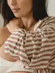 Pregnant model rubs her shoulder.