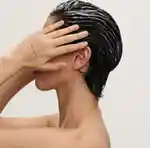 A person with wet, slicked back brown hair covering their face