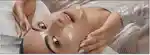 Stylised image of actress Camila Mendes reclining on a bed with a face mask on.