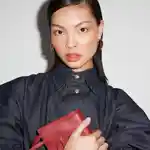 Model holding a red handbag, wearing a similarly red blushed makeup look.