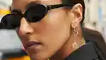 Close-up of a model wearing sunglasses, showing off her many Maria Tash ear piercings, on a New York street.