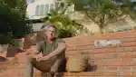 Richard Christiensen, founder of Flamingo Estate, sitting on the stairs outside his home