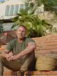 Richard Christiensen, founder of Flamingo Estate, sitting on the stairs outside his home