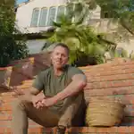 Richard Christiensen, founder of Flamingo Estate, sitting on the stairs outside his home