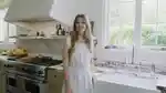 Moon Juice Founder Chantal Bacon in her kitchen in California wearing a white dress