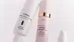 Close up of two retinol serums on a pink background.