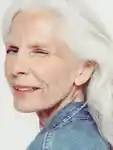 Side profile shot of a grey-haired model winking at the camera.