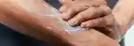 closeup of a man rubbing lotion into his arm