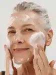 Mature lady washing her face with facewash
