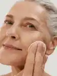 Mature lady using face essence in her skincare routine