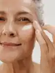 Mature lady applying an eye mask in her skincare routine