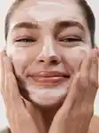 close up of girl washing her face and smiling with foaming cleanser on her face